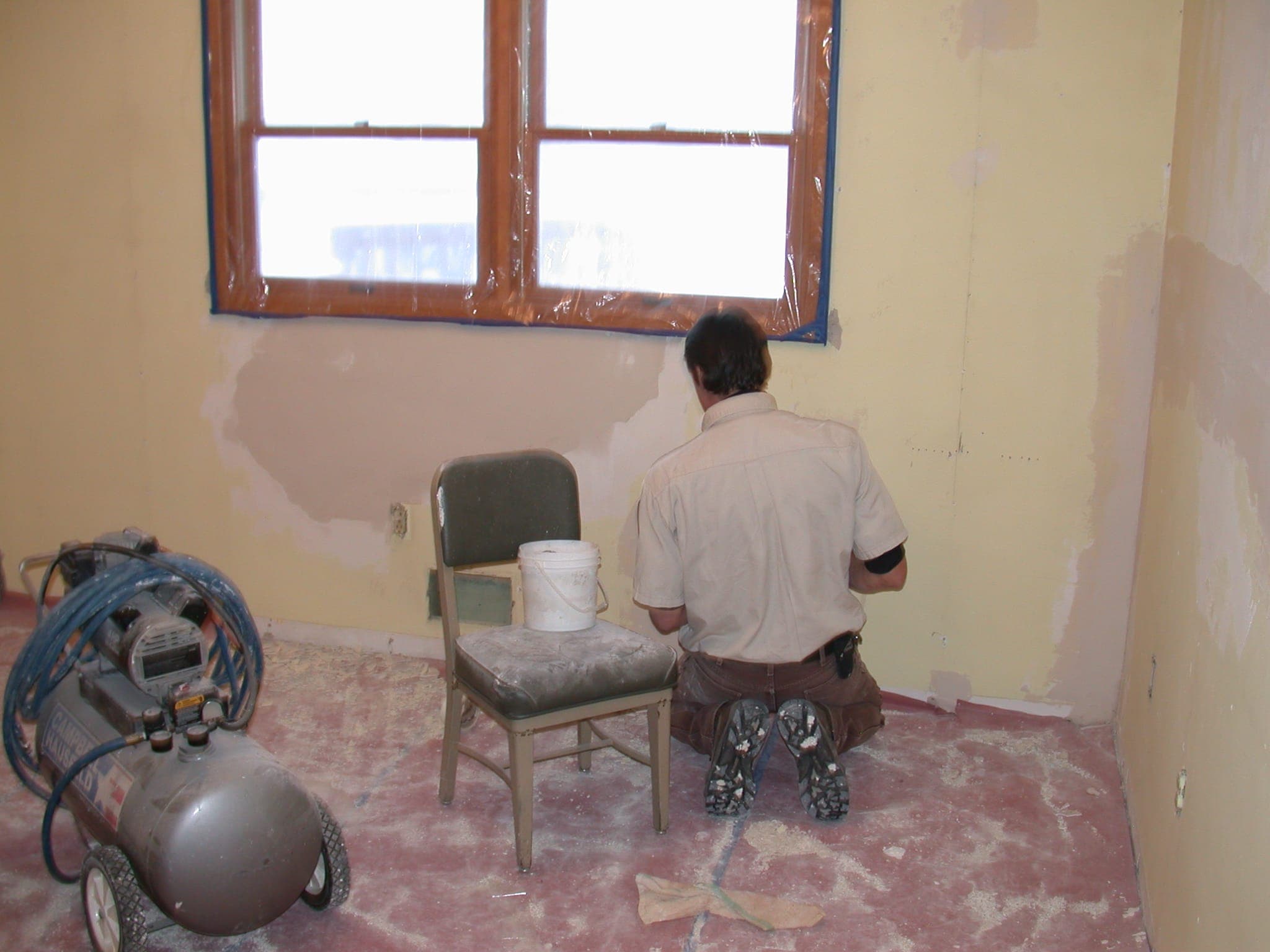 A worker patching walls in an empty room before painting