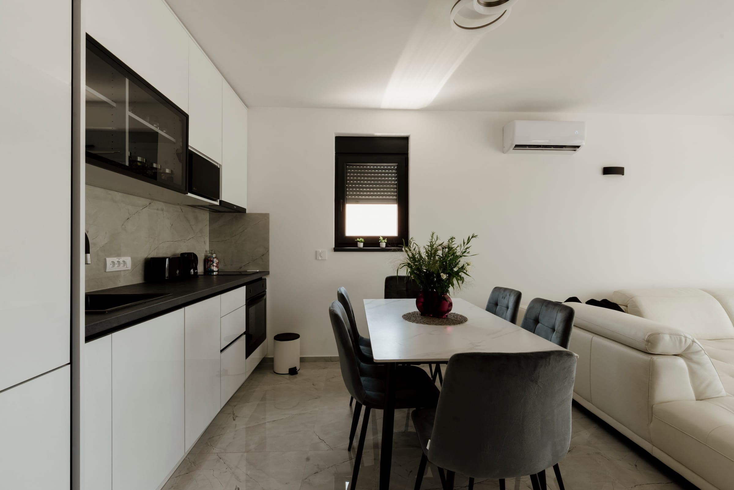 A modern apartment kitchen with white base cabinets and a dining table