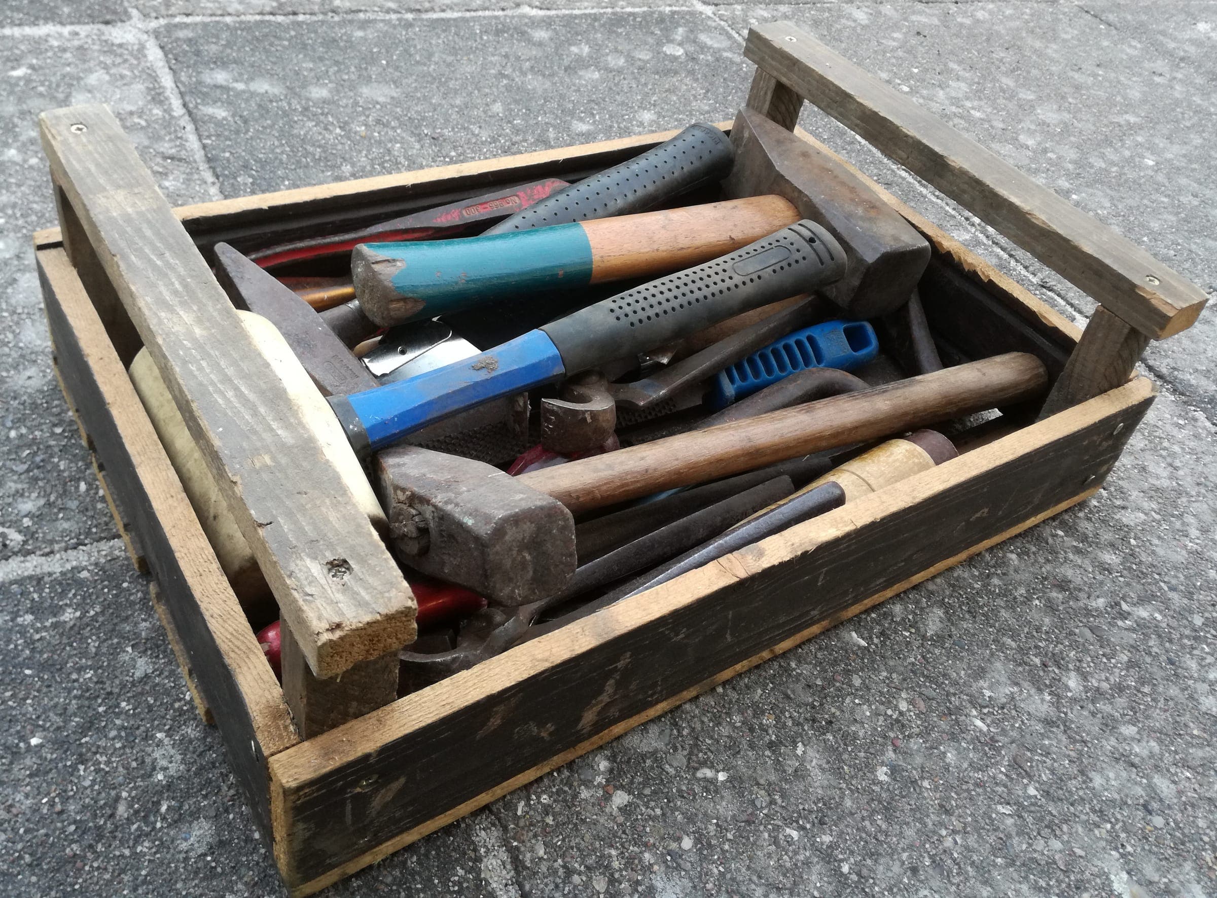 A wooden toolbox full of hammers and hand tools
